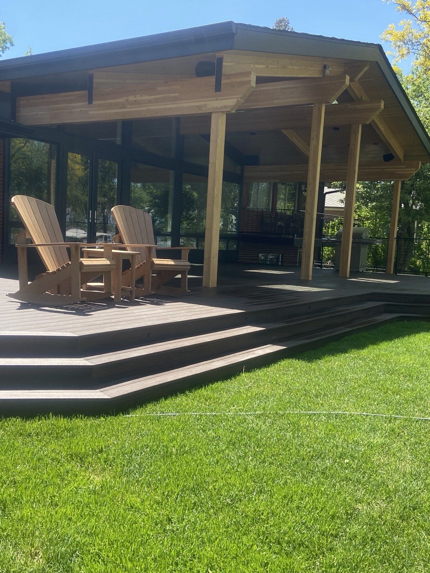 Covered cedar deck addition with vaulted gable roof and Adirondack chairs