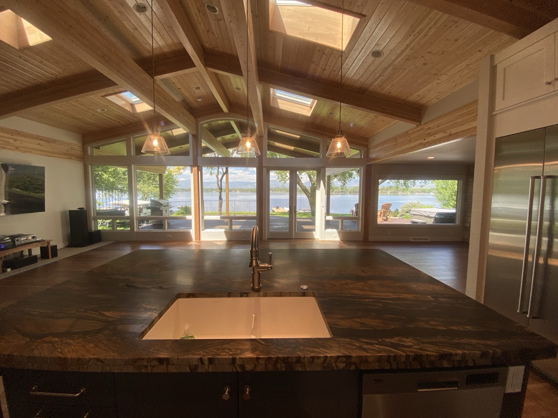 Open-concept lakefront kitchen with live-edge island and vaulted cedar ceiling