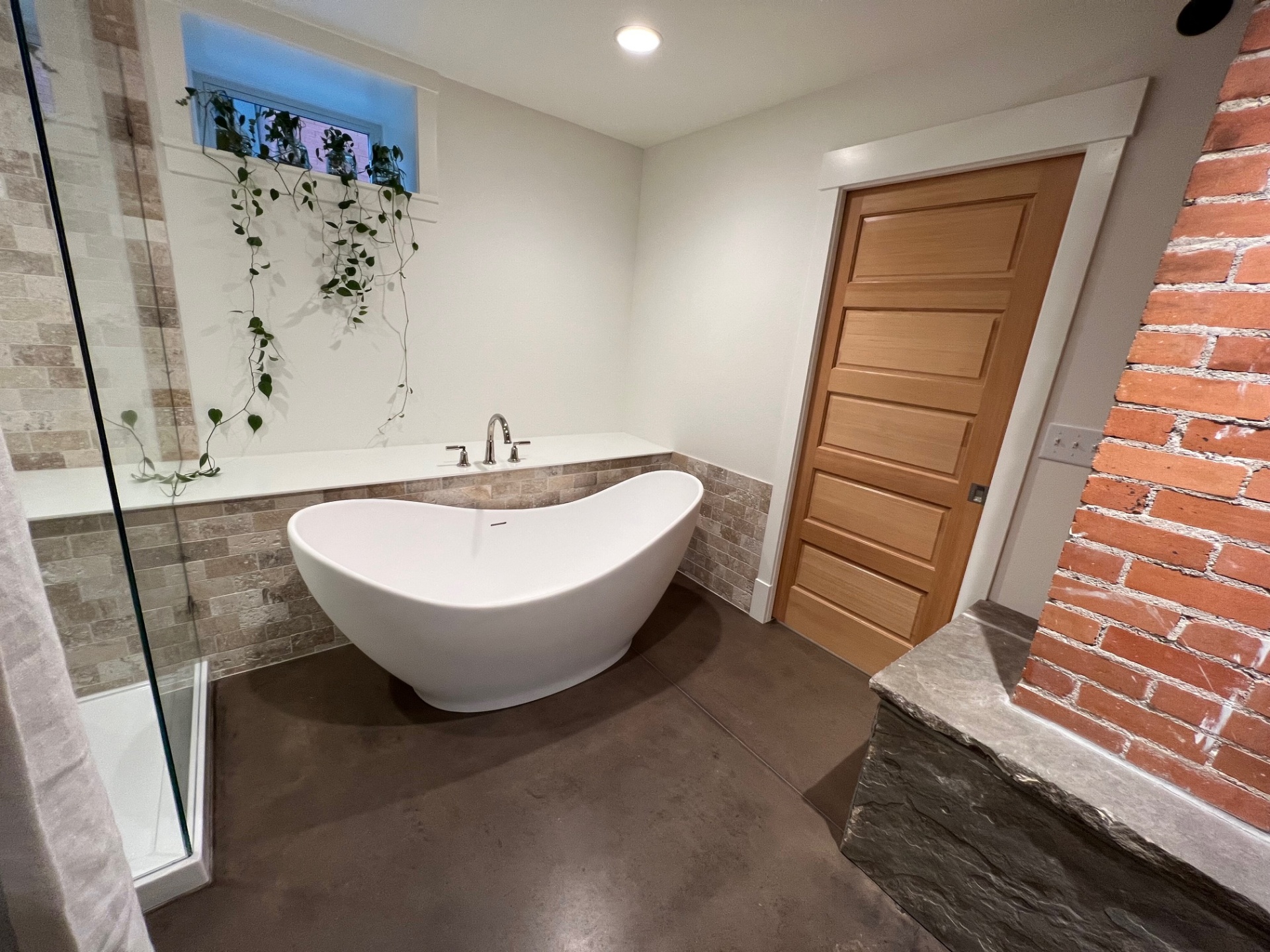 Modern bathroom remodel with freestanding tub and brick accent wall